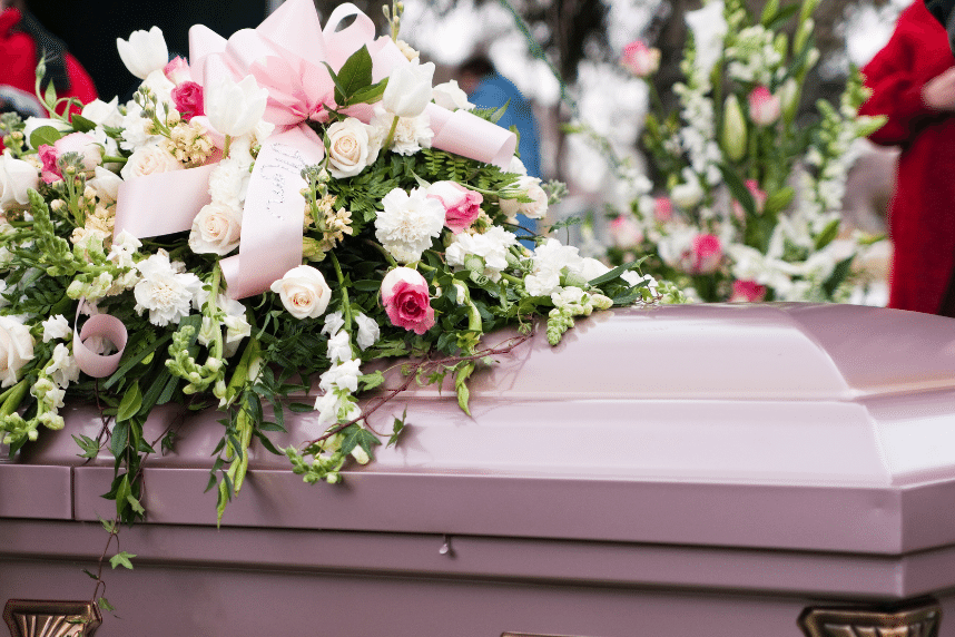 En rosa gravsten med rosa blommor under en färgladd begravning